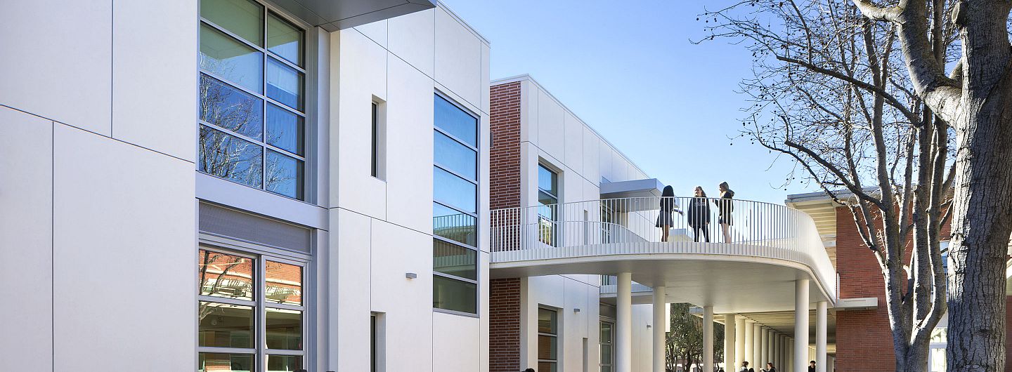 During passing period, a handful of students sit on benches and walk past the Jean Hofmann Center for Innovation